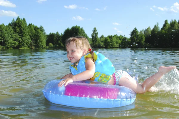 En liten flicka simmar i floden. — Stockfoto