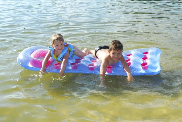 Καλοκαίρι στο ποταμό αγόρι και κορίτσι που επιπλέουν σε ένα στρώμα αέρα. — Φωτογραφία Αρχείου