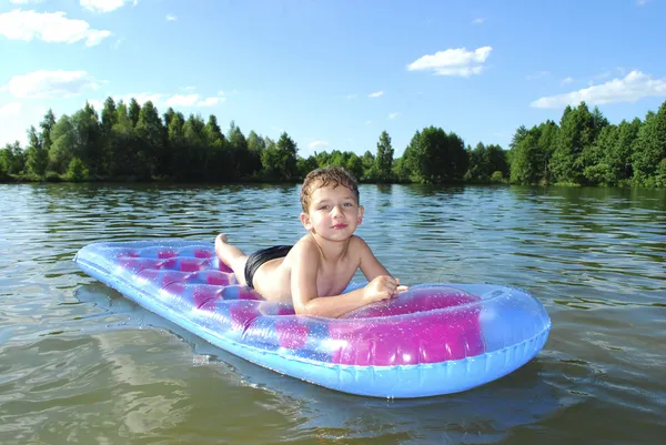 Een kleine jongen zwemt in de rivier. — Stockfoto