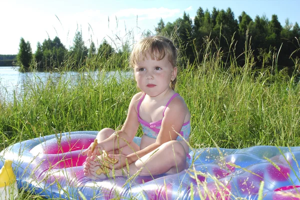 Picknick. liten flicka sitter på gräset vid sjön — Stockfoto