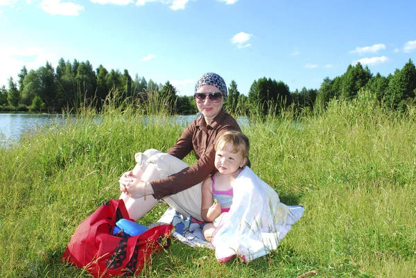 Picnic. Mother with her daughter sitting on the grass near the l — Stock Photo, Image