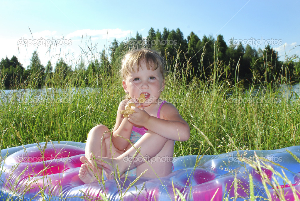 Picnic. Little girl sitting on the grass near the lake — Stock Photo