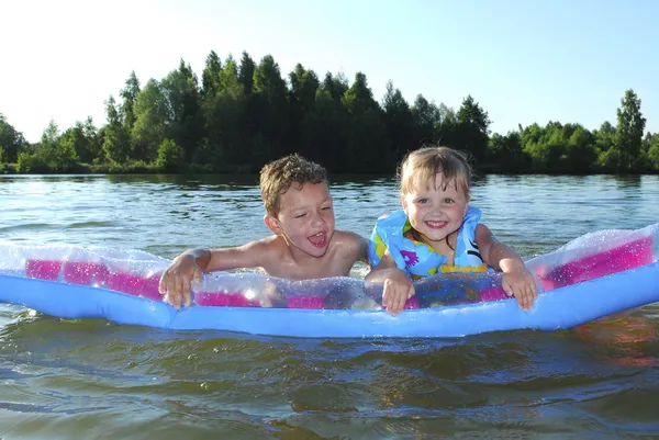 Lato na rzece chłopiec i dziewczynka na dmuchany materac. — Zdjęcie stockowe
