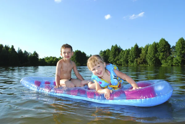 Nyáron a folyó fiú és a lány egy gumimatrac úszó. — Stock Fotó