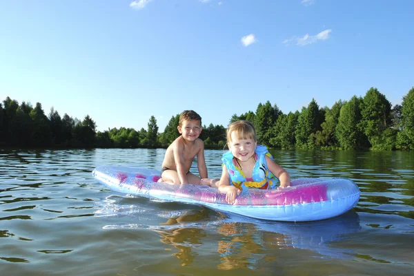 Verano en el río chico y chica flotando en un colchón de aire . —  Fotos de Stock