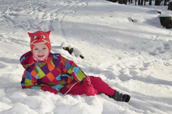 Klein meisje in de sneeuw in het dennenbos liggen. — Stockfoto
