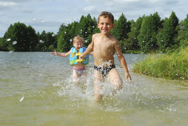 En verano, el río complacer a niño y niña, que están alcanzando — Foto de Stock
