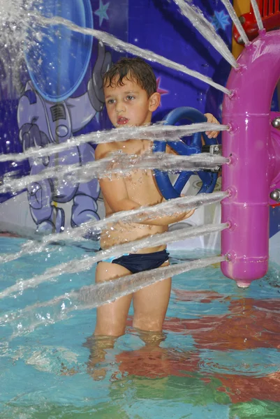 Menino no parque aquático espirra jato de água — Fotografia de Stock