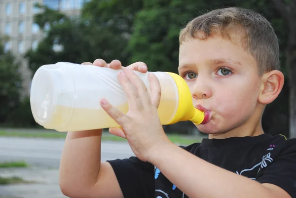 Gatan pojke dricker vatten ur en flaska. — Stockfoto