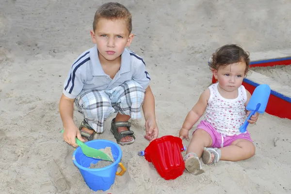 Брат и сестра играют на песке на детской площадке . — стоковое фото