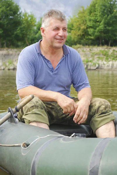 Um homem senta-se no rio em um barco . — Fotografia de Stock