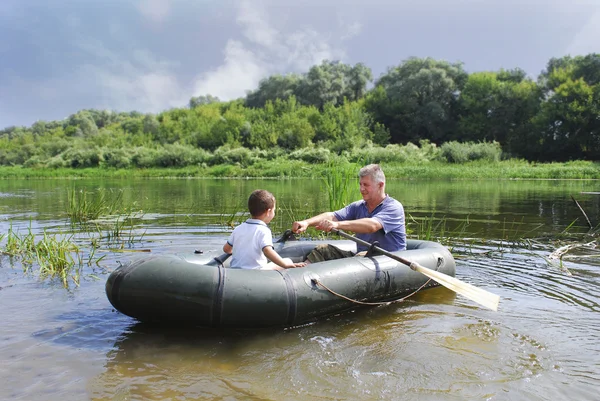 Grandfather with grandson swim in a rubber boat on the river. — Stock Photo, Image