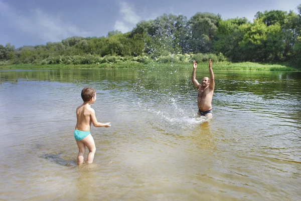 Summer on the river father and son swimming, sprinkles. — Stock Photo, Image