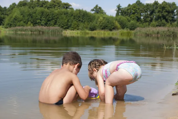 Młody dzieci bawiące się na plaży w pobliżu jeziora. — Zdjęcie stockowe
