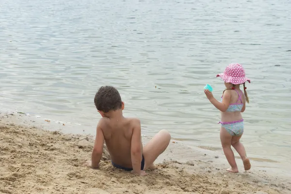 Crianças brincando na praia perto do lago . — Fotografia de Stock