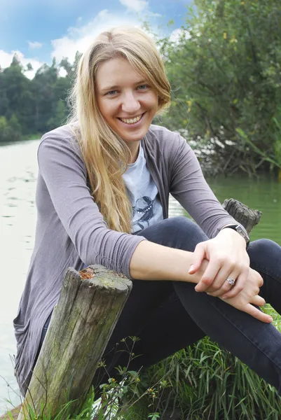 Flicka sitter på stranden av sjön. — Stockfoto