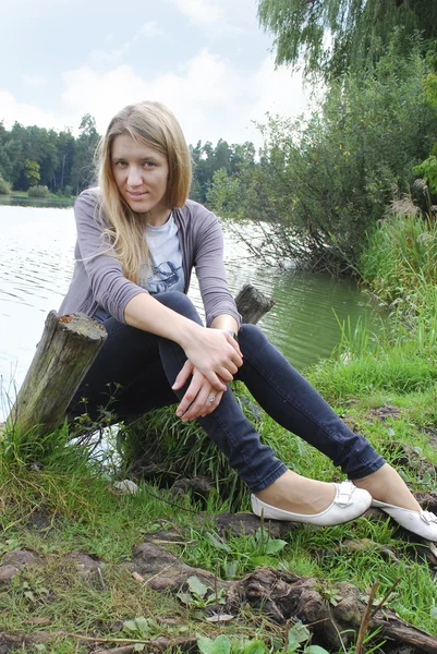 Menina sentada na margem do lago . — Fotografia de Stock