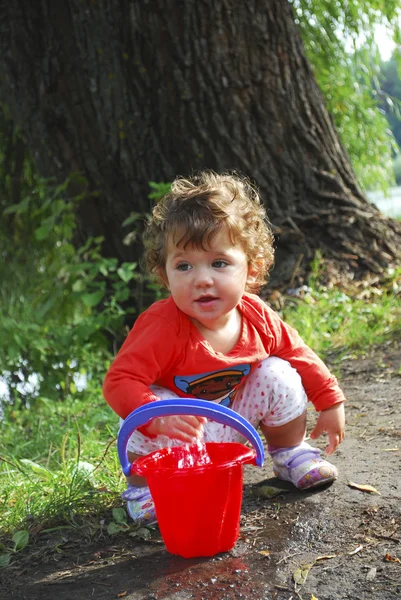 Zomer in de buurt van de rivier meisje spelen met een emmer water — Stockfoto