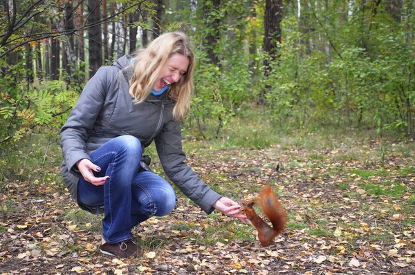 Kobieta w lesie wiewiórka gryzie rękę. — Zdjęcie stockowe