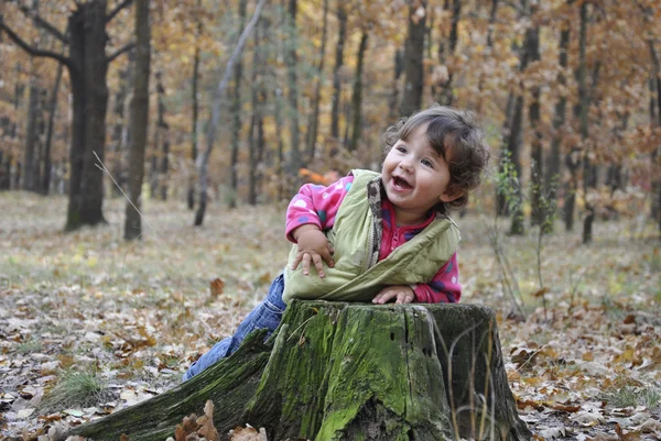 W lesie dziewczynka gra w pobliżu kikut. — Zdjęcie stockowe