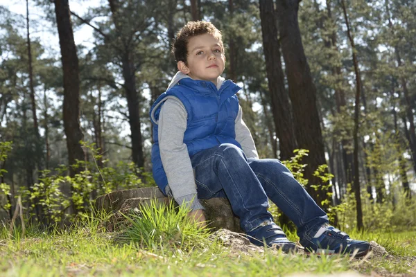 Grönögda pojken sitter i skogen. — Stockfoto