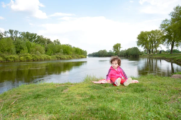 Kleines Mädchen am Fluss sitzend. — Stockfoto