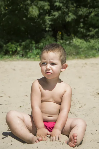 Küçük kız bir plaj kum oturur. — Stok fotoğraf
