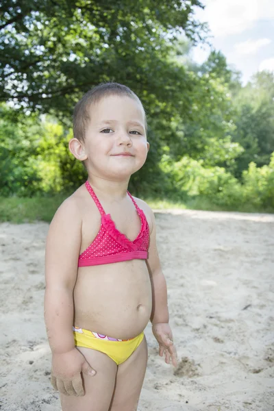 Bambina in costume da bagno in piedi sulla spiaggia vicino al bus — Foto Stock