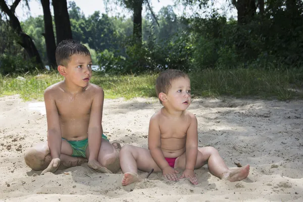 Sommer am Strand sitzen auf dem Sand zwei Kinder und beobachten c — Stockfoto