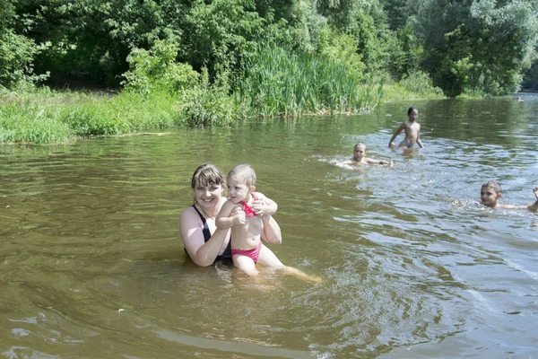 Mother with a small daughter swimming in the river.