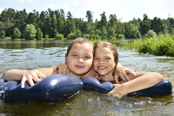 Дві дівчини подружки на літньому озері плавають в озері і смокчуть Стокове Фото