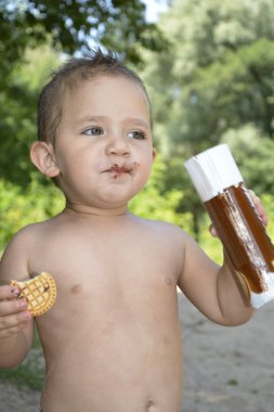 Funny little baby eats cookies. clipart