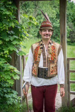Yazın, otantik Ukrayna ulusal kostümlü bir adam Pirogovo Müzesi 'ndeki bir barakanın arka planına karşı..