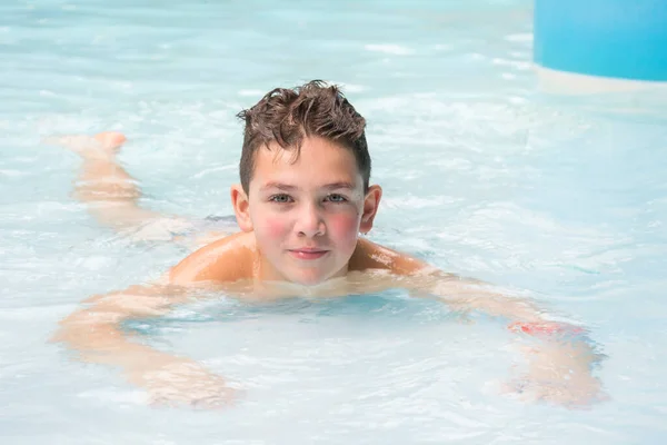Ein Kleiner Fröhlicher Junge Liegt Und Spielt Pool Des Wasserparks lizenzfreie Stockfotos