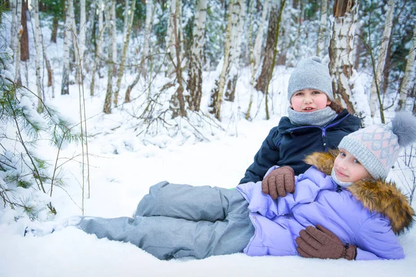 二人の幸せな女の子のガールフレンドは雪の森の中の雪の上に横たわっています — ストック写真