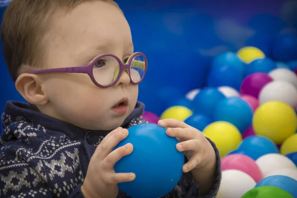 Malý Chlapec Modrém Svetru Brýlemi Hraje Barevnými Plastovými Koulemi Herně — Stock fotografie