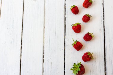 Olgun kırmızı çilek, ahşap beyaz arka plandaki çerçeve gibi bir desen içinde yatar. Uzayı kopyala Yukarıdan görüntüle