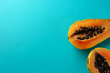 Yaz kompozisyonu. İkiye bölünmüş tropikal papaya meyveleri mavi arka planda yatar. Yaz kavramı. Düz konum, üst görünüm, kopyalama alanı.