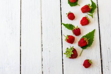Olgun kırmızı çilek, ahşap beyaz arka plandaki çerçeve gibi bir desen içinde yatar. Uzayı kopyala Yukarıdan görüntüle