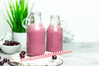 Beyaz arka planda bir şişe vişne suyu, kirazlar toptan ve tabakta. Sabah kahvaltısı.