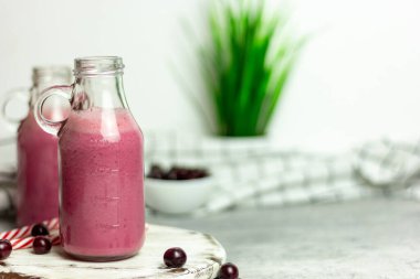 Beyaz arka planda bir şişe vişne suyu, kirazlar toptan ve tabakta. Sabah kahvaltısı.