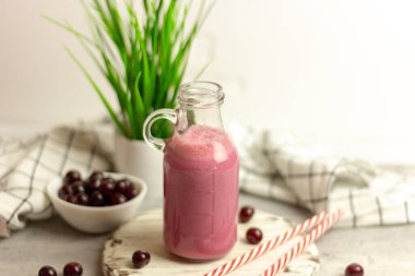 Beyaz arka planda bir şişe vişne suyu, kirazlar toptan ve tabakta. Sabah kahvaltısı.