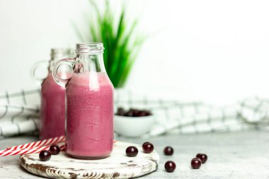 Beyaz arka planda bir şişe vişne suyu, kirazlar toptan ve tabakta. Sabah kahvaltısı.