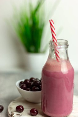 Beyaz arka planda bir şişe vişne suyu, kirazlar toptan ve tabakta. Sabah kahvaltısı.