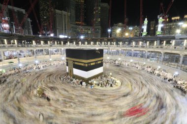 Umra ya da Hac zamanlarında Mekke 'deki Kutsal Kabe' nin etrafında Tawaf yapan bir grup insan Mescid-i Haram 'ın tepesinden bakıyor. Geceleri uzun pozlama