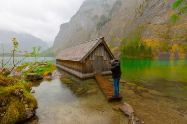Yaz aylarında mavi gökyüzü ve bulutlar ile güzel bir güneşli bir günde doğal Obersee Gölü'nde geleneksel eski ahşap tekne evi Pastoral görünümü, Millipark Berchtesgadener Land, Bavyera, Almanya