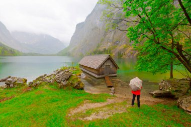 Yaz aylarında mavi gökyüzü ve bulutlar ile güzel bir güneşli bir günde doğal Obersee Gölü'nde geleneksel eski ahşap tekne evi Pastoral görünümü, Millipark Berchtesgadener Land, Bavyera, Almanya