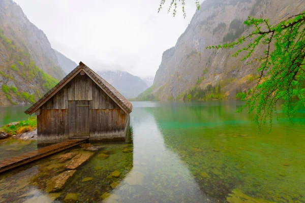 Yaz aylarında mavi gökyüzü ve bulutlar ile güzel bir güneşli bir günde doğal Obersee Gölü'nde geleneksel eski ahşap tekne evi Pastoral görünümü, Millipark Berchtesgadener Land, Bavyera, Almanya