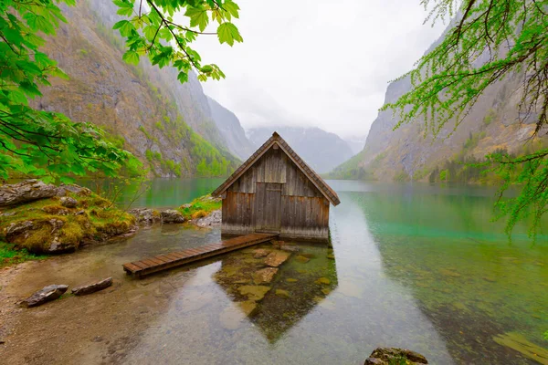 Yaz aylarında mavi gökyüzü ve bulutlar ile güzel bir güneşli bir günde doğal Obersee Gölü'nde geleneksel eski ahşap tekne evi Pastoral görünümü, Millipark Berchtesgadener Land, Bavyera, Almanya