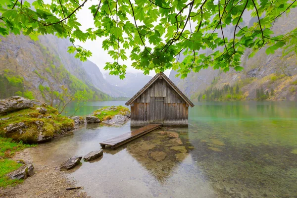 Yaz aylarında mavi gökyüzü ve bulutlar ile güzel bir güneşli bir günde doğal Obersee Gölü'nde geleneksel eski ahşap tekne evi Pastoral görünümü, Millipark Berchtesgadener Land, Bavyera, Almanya